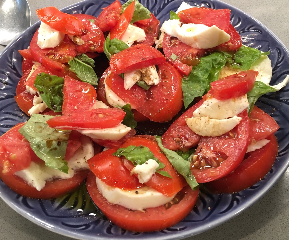caprese salad on a plate: tomato, basil, and mozzarella