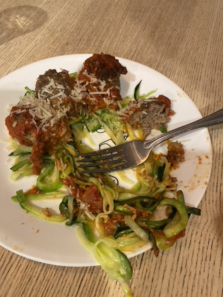 zucchini and meatballs on a plate with a fork